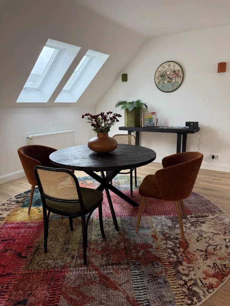 Essbereich der Ferienwohnung mit rundem Tisch unter Dachfenstern