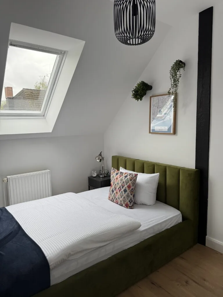 Schlafzimmer mit grünem Bett unter der Dachschräge